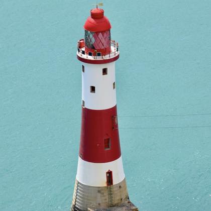 A red and white lighthouse against a blue sky